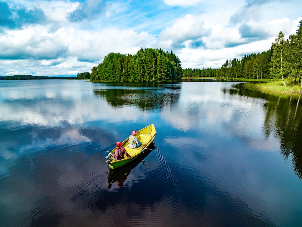 Aufnahme einem See in Finnland. Inmitten ein Boot mit zwei Anglern