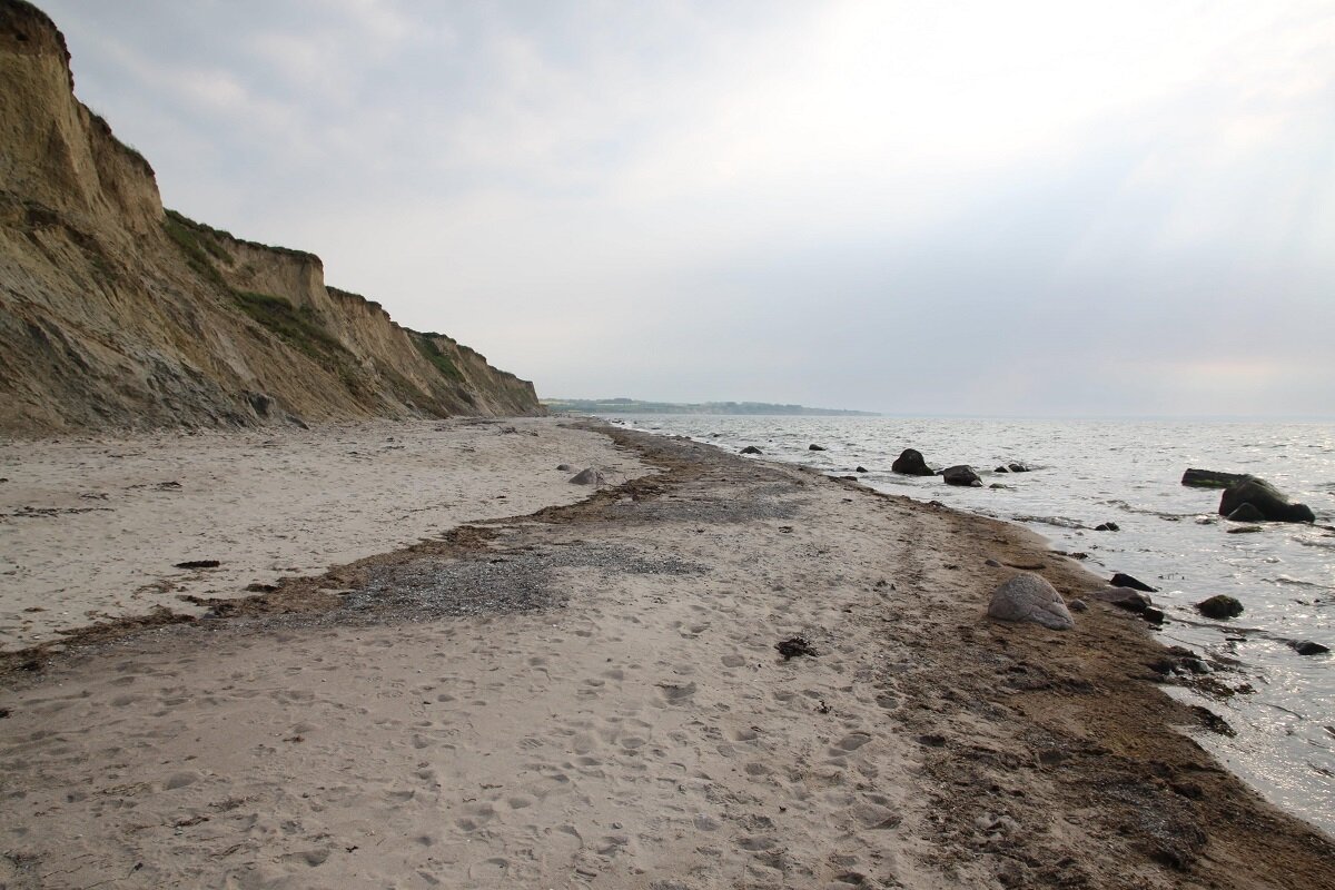 Aufnahme einer Steilküste mit Sand & Steinen sowie dem Meer