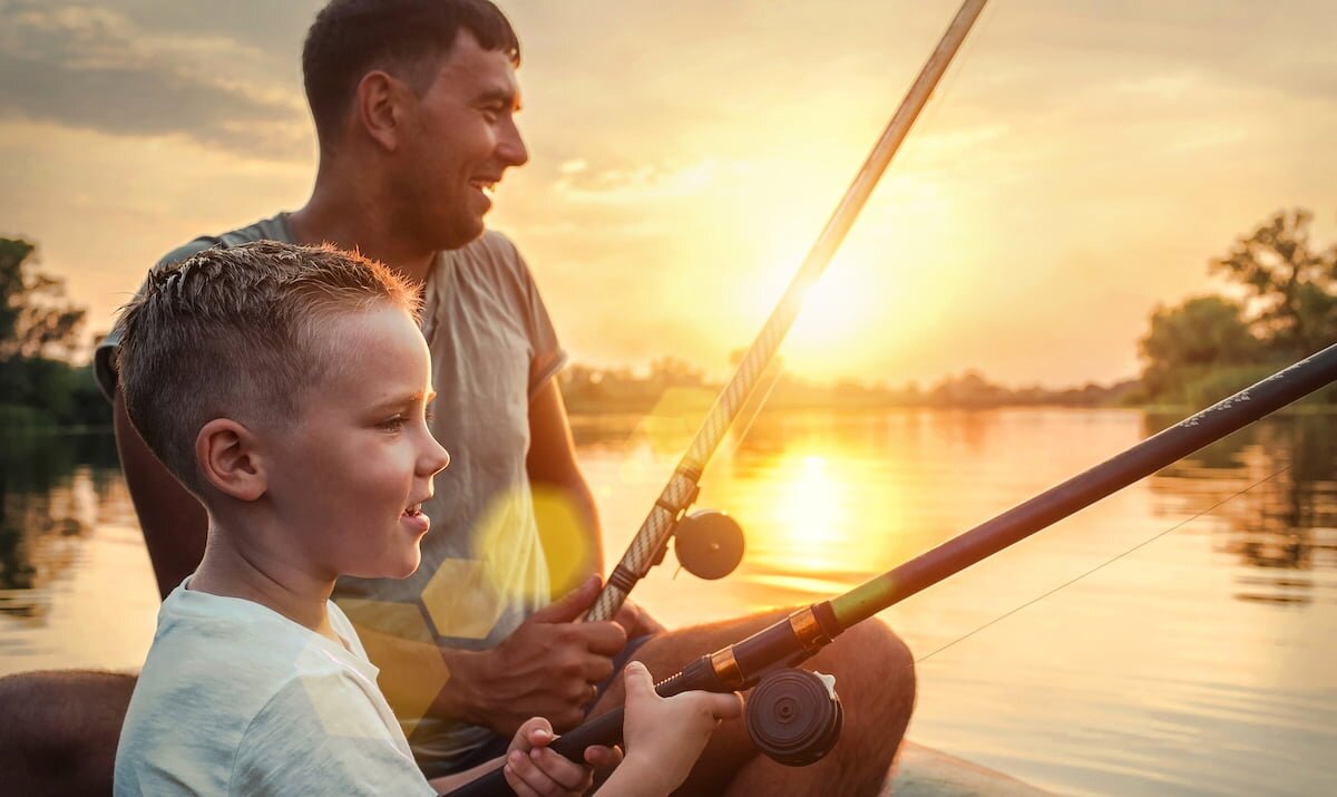 Mann und Kind angeln auf Angelboot. Im Hintergrund der Sonnenuntergang