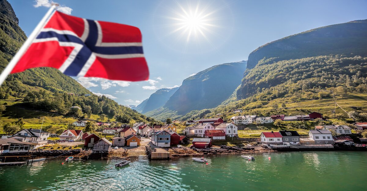 Schönes Panorama eines norwegischen Dorfes am Wasser. Im Vordergrund die Norwegenfahne