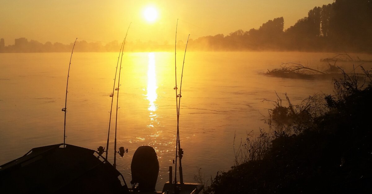 Angeln vom Boot während des Sonnenaufgangs am Fluss.