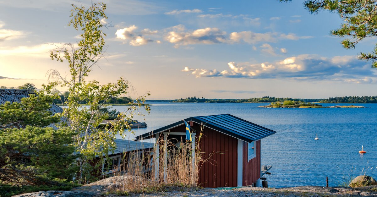 Aufnahme von einer kleinen Holzhütte am See in Schweden bei Tag.