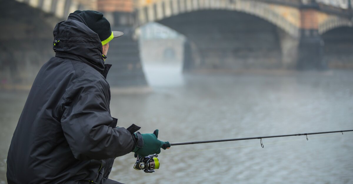 Aufnahme eines Anglers, der mitten in der Stadt angelt. Im Hintergrund Brücke.