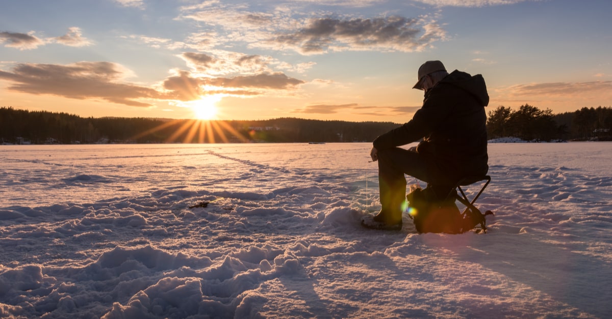 Silhouette eines Mannes Eis fischen auf einem See in Norwegen bei Sonnenuntergang