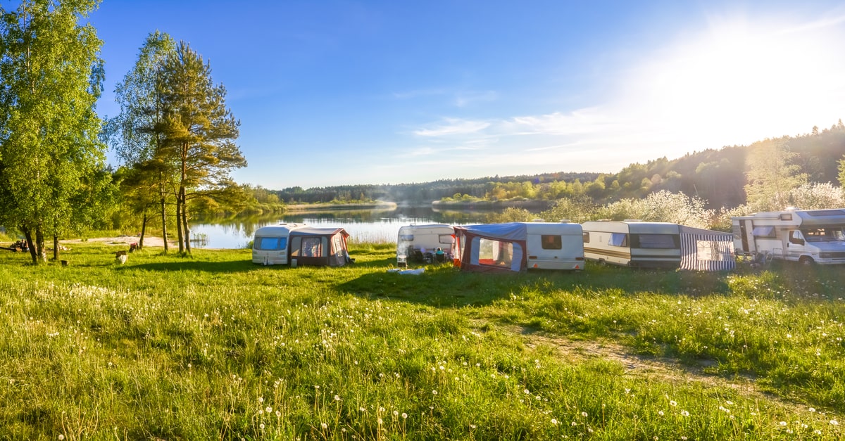 Wohnmobile und Zelte auf einer Wiese vor einem See
