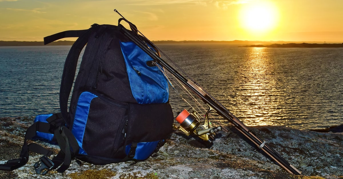 Ein Rucksack und eine Reiserute vor einem See während die Sonne untergeht
