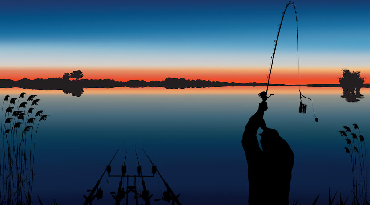 Angler während des Auswurfs eines Futterkorbes, im Hintergrund ein See in der Abenddämmerung
