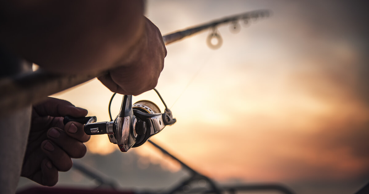 Angler mit Angelrute in der Hand im schönen Sonnenuntergang